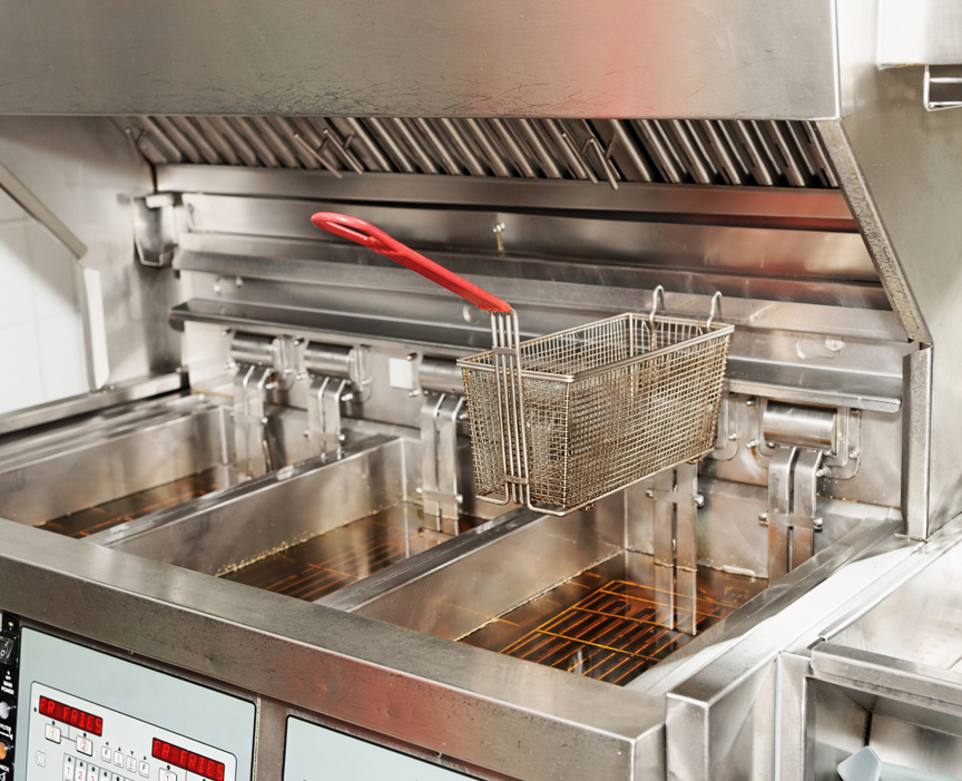 Commercial deep fryer with canopy hood and grease filters visible above