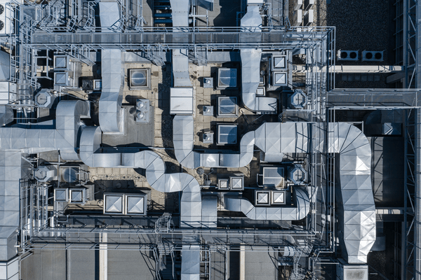 Aerial view of commercial HVAC and exhaust system infrastructure on a building rooftop