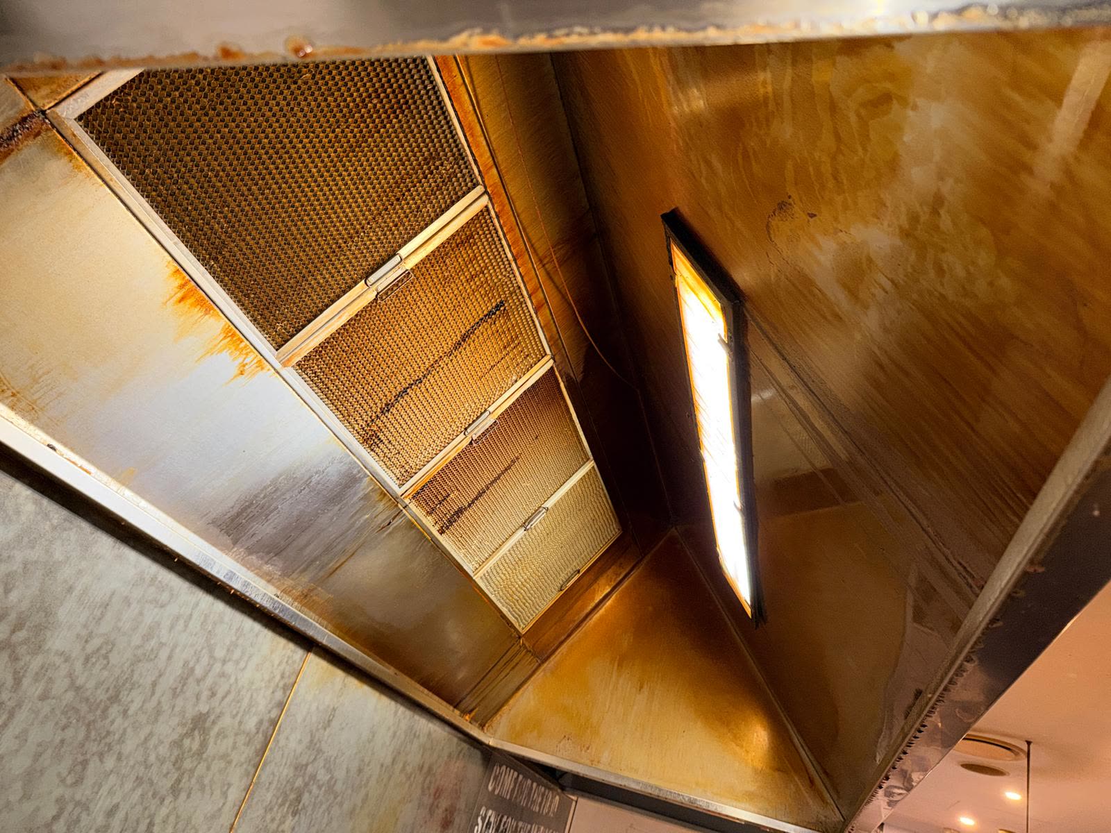 Grease staining visible on a commercial kitchen canopy interior