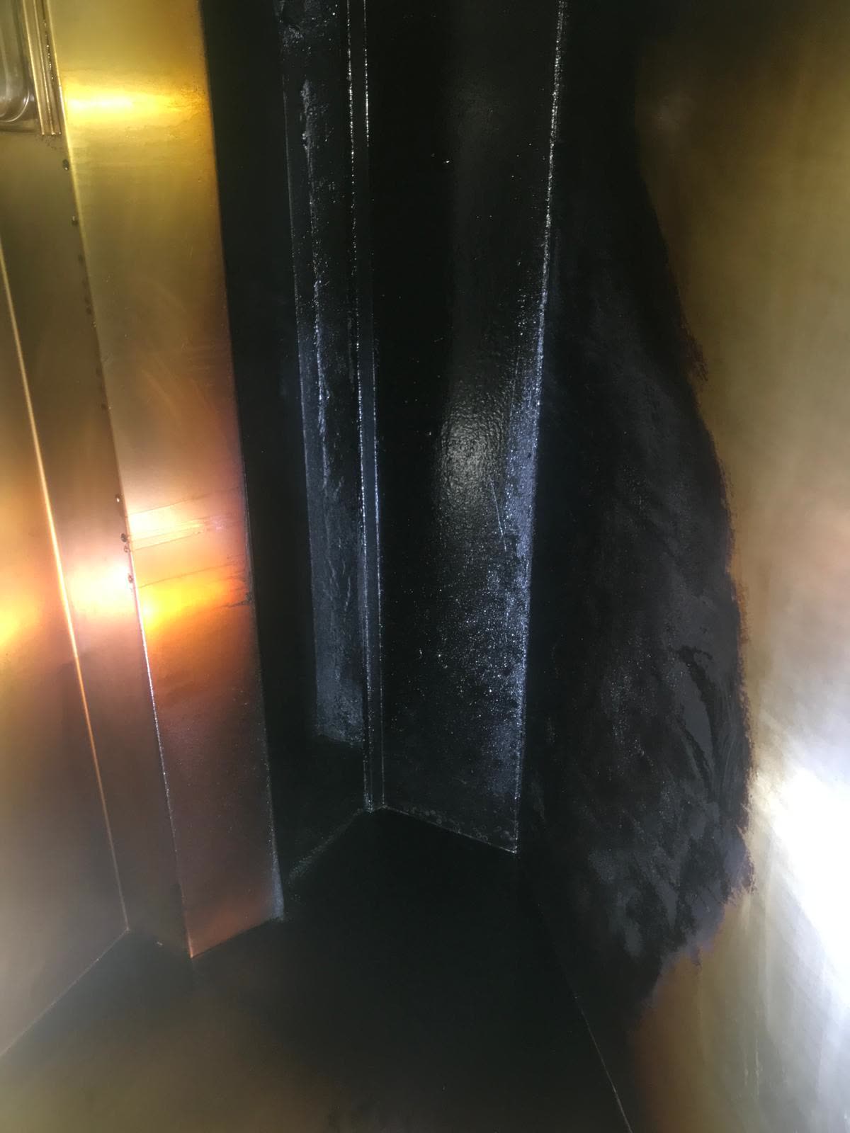Thick tar-like grease coating the interior walls of a commercial kitchen exhaust duct